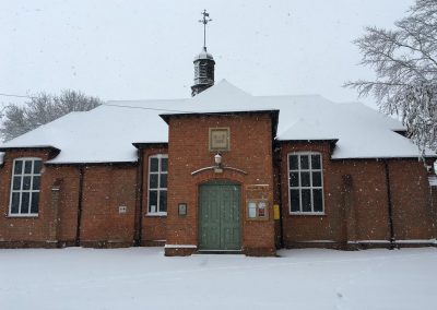 Exterior of Dumbleton Village Hall in winter snow